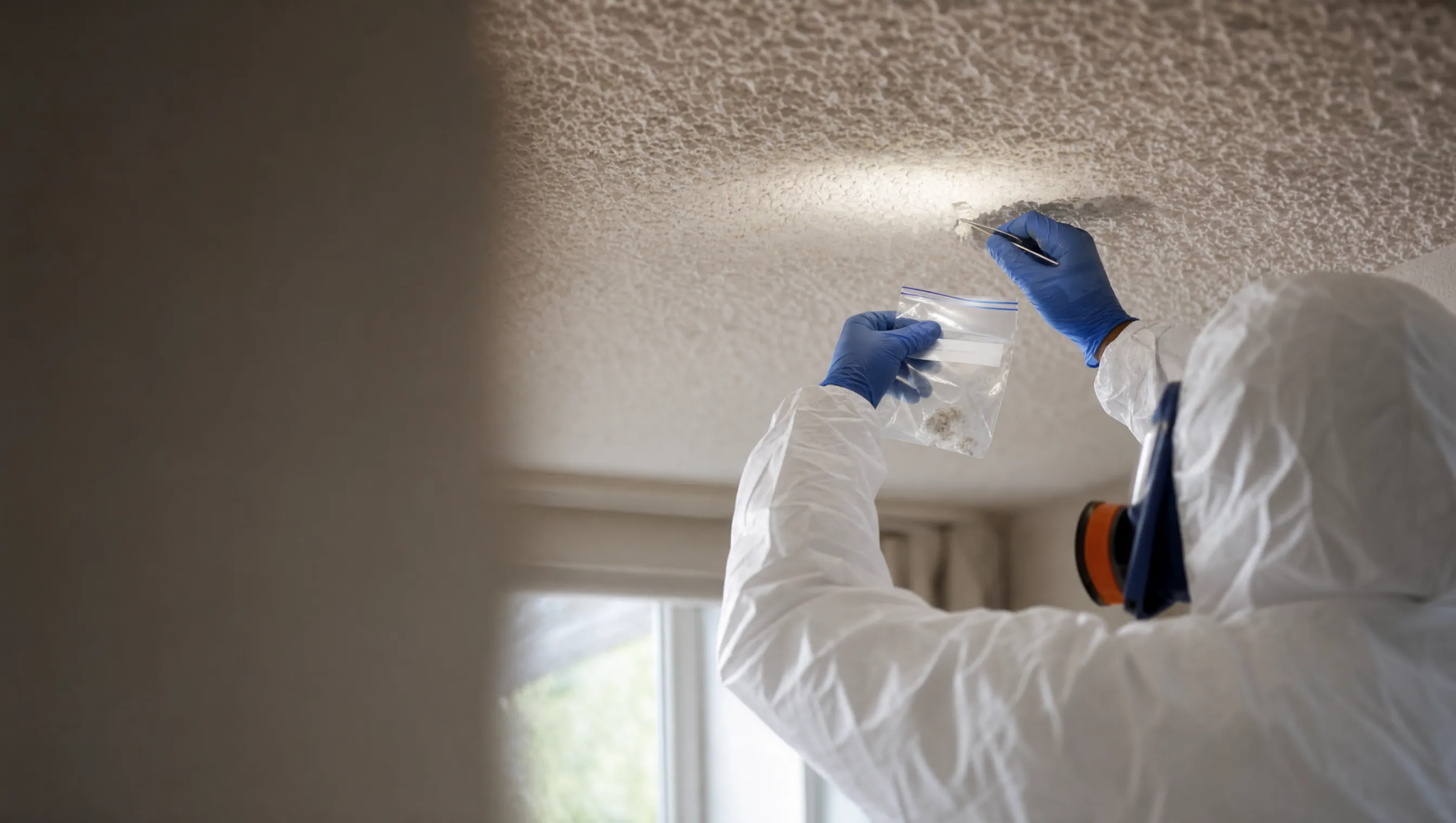 Surveyor sampling a textured ceiling for asbestos